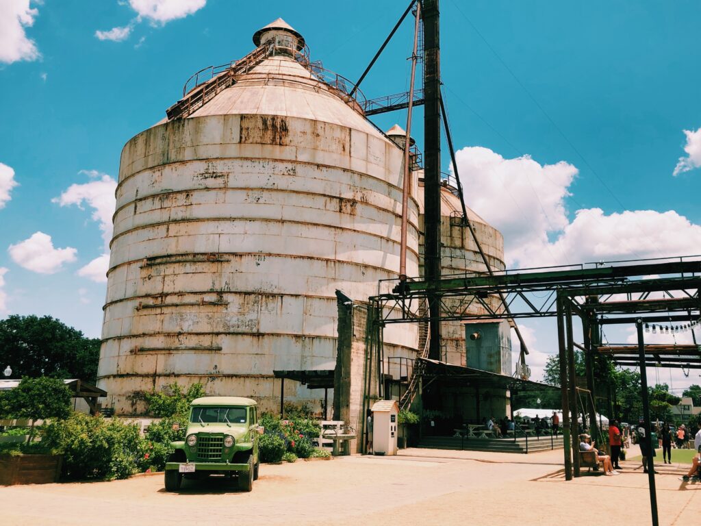 Two large silos with a antique green farm truck next to them that have been remodeled and are not part of the Magnolia brand in Waco, TX