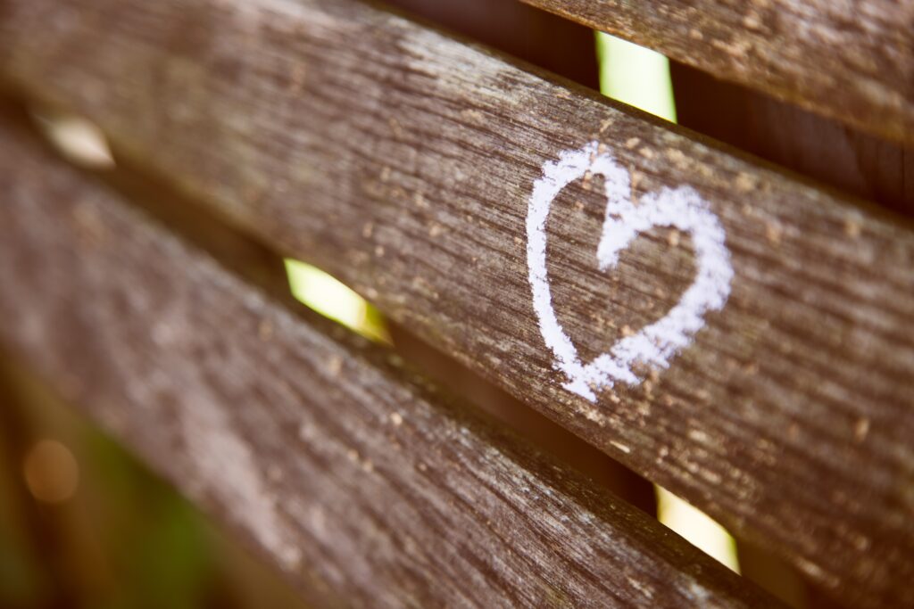 small white chalk heart on natural wood fence 