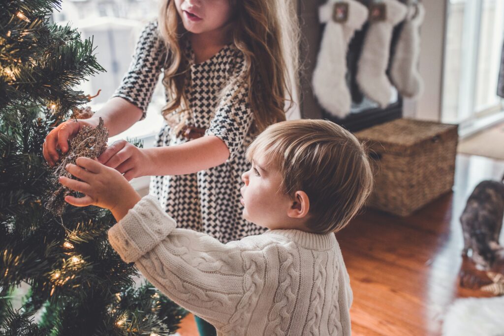 Two children working together to decorate a Christmas tree. 