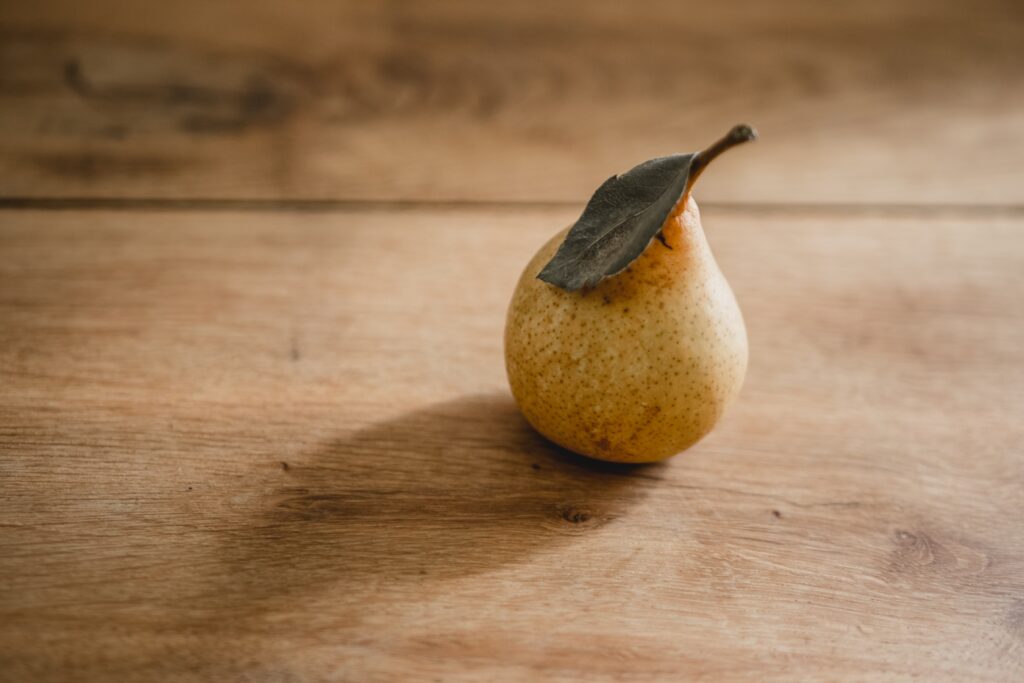 Fresh piece of fruit, a pear, on a clean wood table