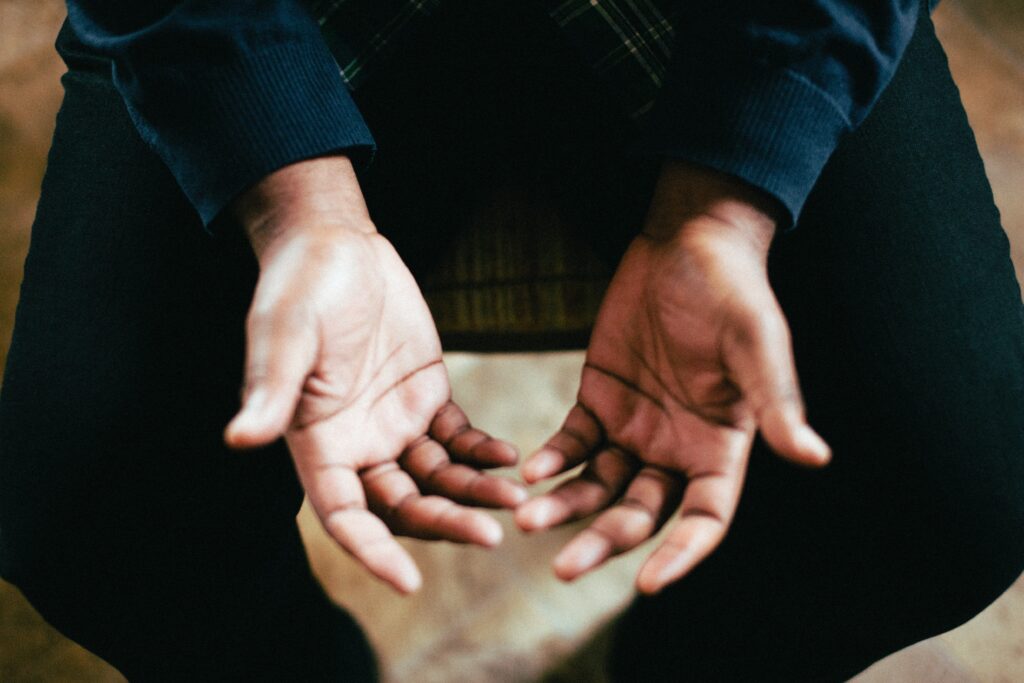 A man's hands held palms up in is lap as a posture of openness or surrender